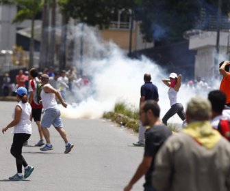 Opposition supporters run past a tear gas cloud as clashes broke out while the Constituent Assembly election was being carried out in Caracas