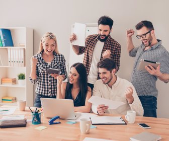 happy young workers raised hands and looking at laptop