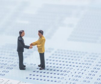 business miniature people shaking hands on book bank background