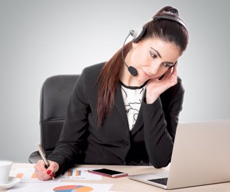 Young female customer support with headset sitting on a desk
