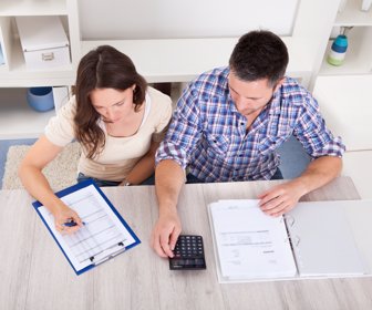 Portrait Of A Young Couple Calculating Finance At Desk