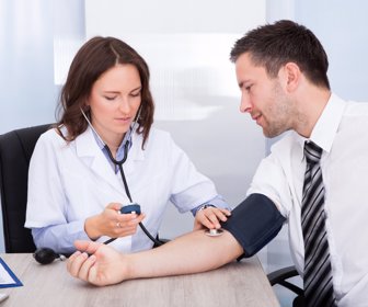 Female Doctor Checking Blood Pressure Of Young Businessman
