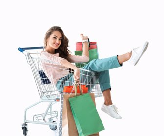 happy beautiful girl sitting in shopping cart with bags, isolated on white