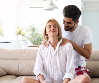 Man giving massage to his wife at home