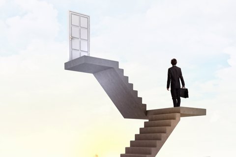 Businessman walking up staircase to door in sky